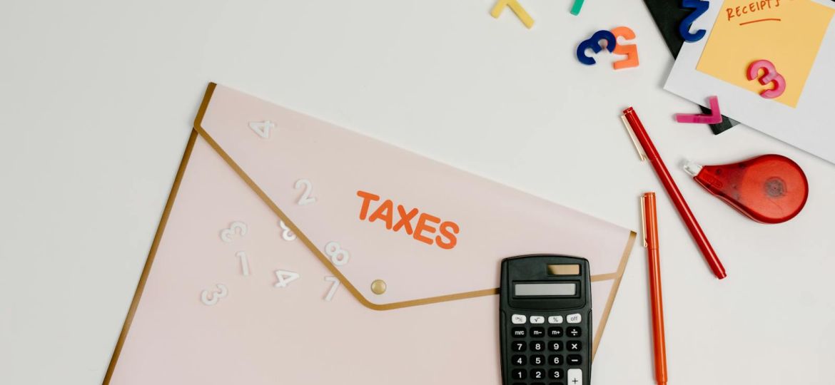 Flat lay of a tax preparation workspace with calculator, envelope, and colorful numbers.