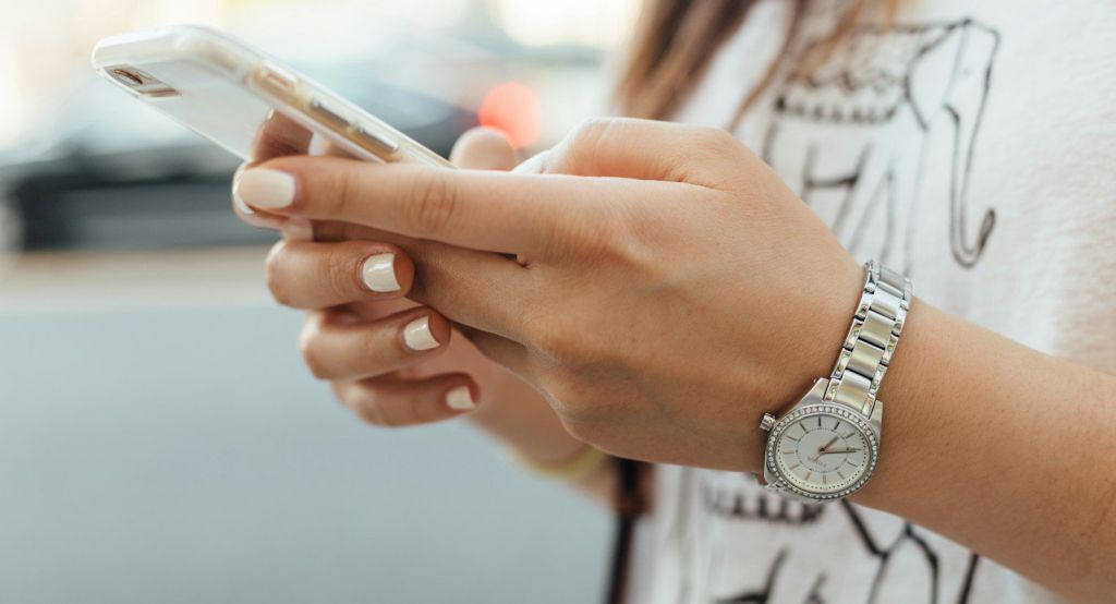 woman holding iPhone during daytime